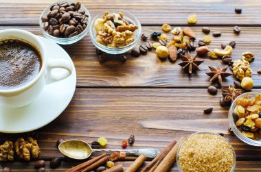 Sağlıklı aperatifler - fındık ve kuru üzüm doğal ahşap zemin üzerine siyah espresso kahve fincan. Kopya alanı orta.