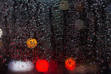 Pencere camına bokeh ışıkları ile gece yağmur damlaları