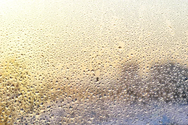 雨のしずくとウィンドウ ガラス背景 ゴールデン シルバー色の凍結する水 — ストック写真