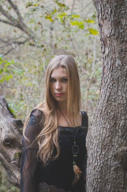 Uzun saçlı sarışın bir Fantasy siyah elbise bir sonbahar ormanında, korkunç Cadılar Bayramı peri masalı