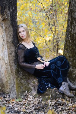 Uzun saçlı sarışın bir Fantasy siyah elbise bir sonbahar ormanında, korkunç Cadılar Bayramı peri masalı