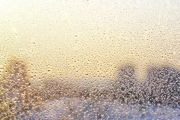 Gotas de lluvia y agua congelada en el fondo de cristal de la ventana — Foto de Stock