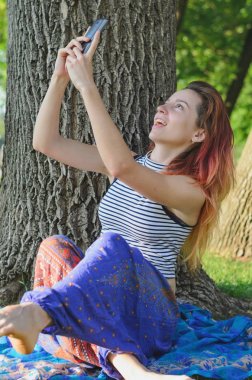 Parkta yüzler yapan ve selfie çeken, cep telefonuyla eğlenen kız