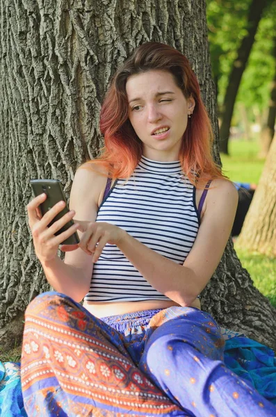 Dívka Parku Kde Dělá Obličeje Dělá Legraci Baví Mobilním Telefonem — Stock fotografie