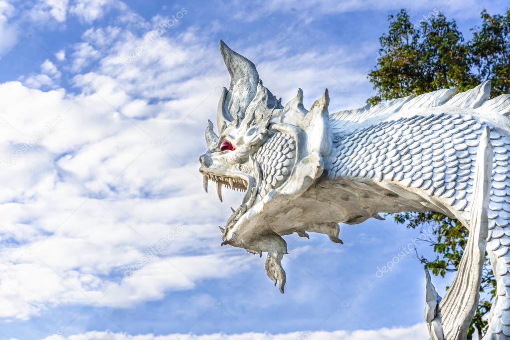 Close up sculpture head of white Naga or Phrayanak with blue sky and cloud background