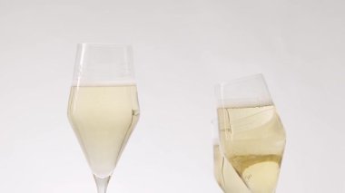 Hands of happy friends cheering celebrating holidays with wine.say a toast, Crop unrecognizable people clinking elegant crystal glasses of champagne against white background during festive event.