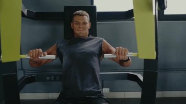 Young man working out on gym equipment, focusing on strength training and physical fitness in a modern gym environment. Young Man Exercising on Gym Equipment for Strength Training and Fitness