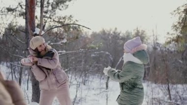 Joyful family having fun outdoors with a playful snowball fight in a snowy forest. Winter joy and family bonding captured in a serene setting. Family Enjoying a Snowball Fight in Winter Forest