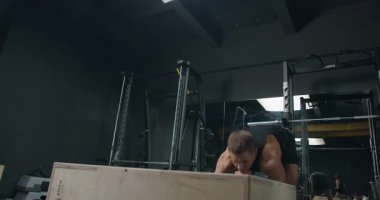 An image showcasing a young adult male energetically working out, wiping sweat with a towel in a well-equipped, modern gym. Young Man Exercising Intensely in a Modern Gym Setting