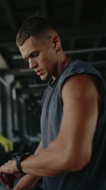 Young man in gym, showcasing determination and focus. Ready for workout in modern fitness center. Represents fitness, health, and dedication. Focused Man in Gym Setting Preparing For Workout Vertical