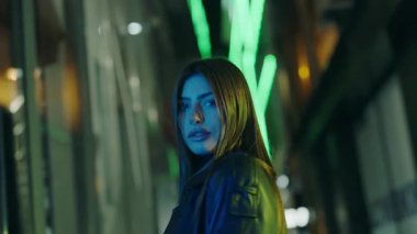 Model posing urban avenue. Pretty female person posing in city center at night. Beauty lady on street. Slow motion. Portrait of confident gorgeous female looking at camera while walk in evening city