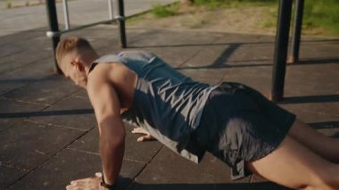 A man exercises by doing push-ups on an outdoor pavement. The setting is urban and sunny, symbolizing dedication and fitness. Perfect for health, exercise, and motivation themes.Man Performing Outdoor