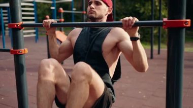 A young athletic man performs pull-ups on a horizontal bar on a street sports ground. The concept of a healthy lifestyle, fitness, and sports.