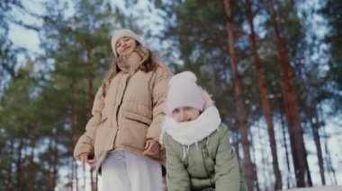 A heartwarming image of two smiling children, bundled up in warm jackets and hats, as they experience the joy of a gentle snowfall in a wintery pine forest. Joyful Family Enjoying Snowfall in a Winter