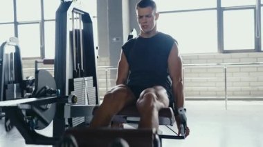 A focused man working out on a leg press machine in a bright gym setting, demonstrating strength training and fitness dedication. Man Exercising at Gym Using Leg Press Machine for Strength Training