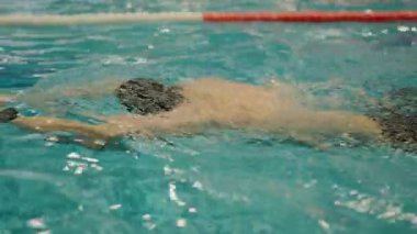Focused male swimmer training in an indoor pool, showcasing determination and strength in a competitive environment. Competitive Swimmer in Action During a Focused Training Session