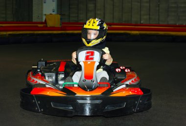 bir go-kart karting yolda kapalı bir kask içinde gülümseyen küçük kız