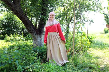 renkli Müslüman giysili genç gülümseyen kadın doğada kamera önünde poz