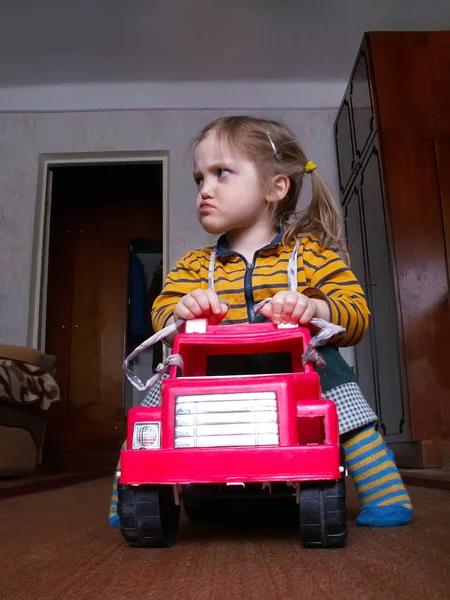 小さな女の子はおもちゃの車の中で座って 面白い顔になります — ストック写真