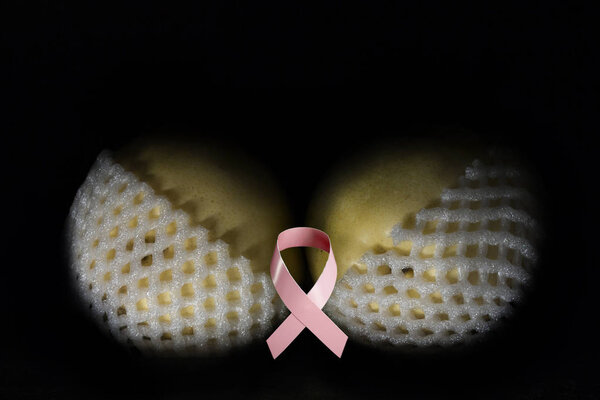 two yellow pears in white shells, similar to a bra with a pink ribbon in the middle, symbolizing the fight against cancer
