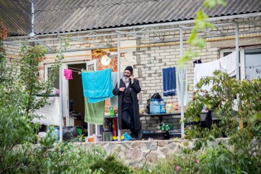 Uman, Ukrayna, 13.09.2015 siyah giysili bir sakallı Yahudi adam eski konut ev verandada telefonla konuşuyor