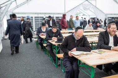 Uman, Ukrayna, 13.09.2015: Kippahs ve siyah elbiseli Yahudi erkekler çoğu kapalı masada oturan ve kitap okumak. Yahudi yeni yılı kutlama Rosh Hashanah, topladıkları
