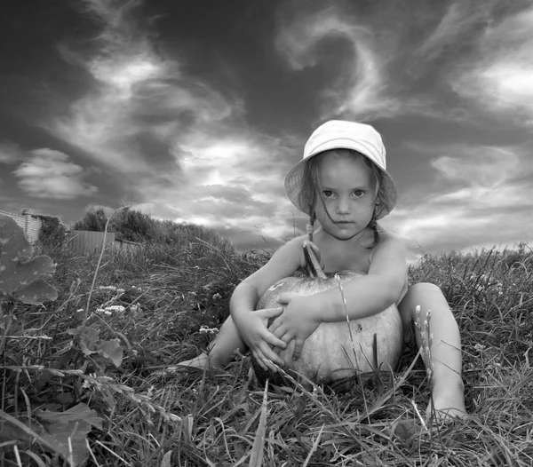 芝生の上のカボチャの少女 黒と白のイメージ — ストック写真
