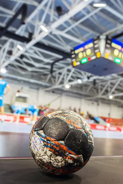 Handball ball on the ground of sport field indoors on the background of scoreboard