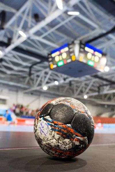 Handball ball on the ground of sport field indoors on the background of scoreboard