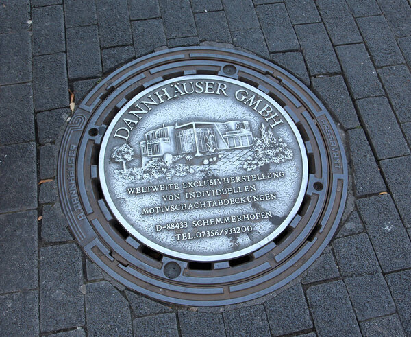 Old sewer manhole on dark cobblestone pavement Mannheim