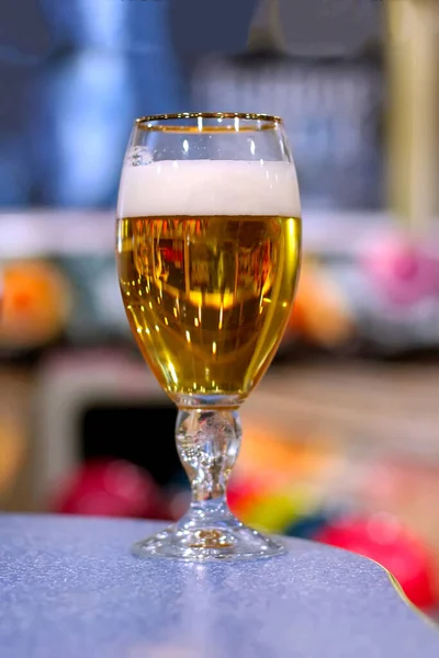 冷たいガラスビールは 多色の背景に青いテーブルの上に立つ — ストック写真