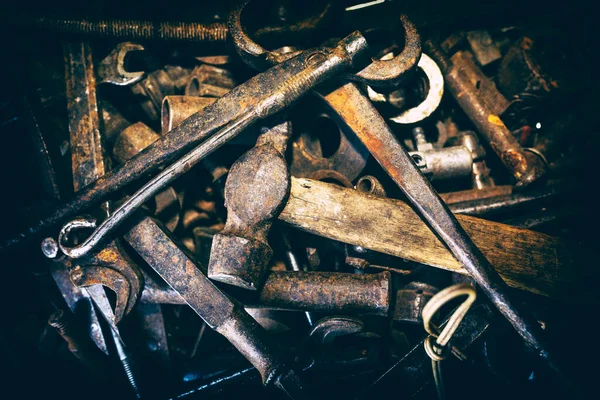 Eski paslı aletler düzensiz. Ön planda bir çekiç, bir ingiliz anahtarı ve bir keski. Arkaplan dokusu kapat.