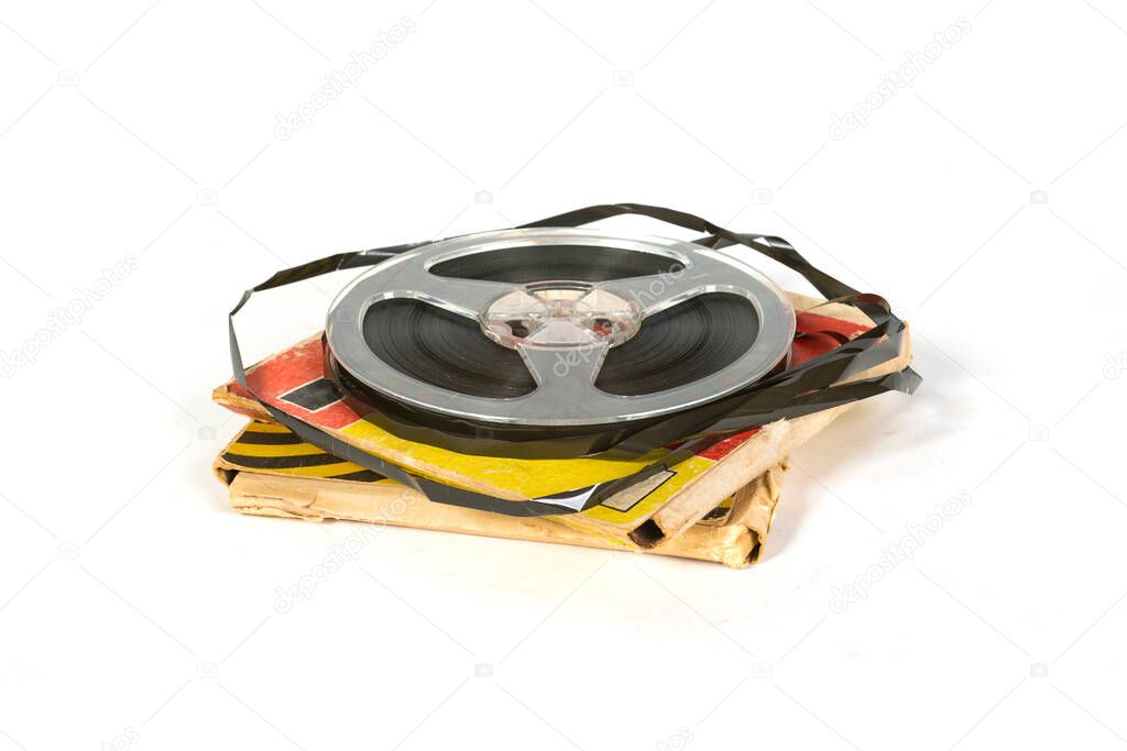 An old brown magnetic tape on a reel that lies on a yellow paper box. on white background.