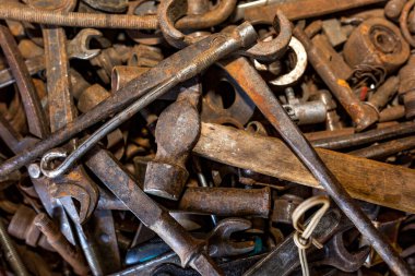 Eski paslı aletler düzensiz. Ön planda bir çekiç, bir ingiliz anahtarı ve bir keski. Arkaplan dokusu kapat.