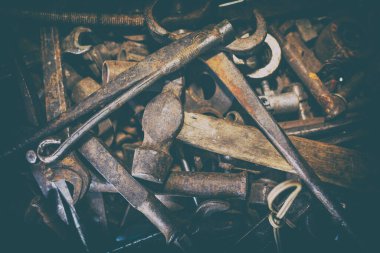 Eski paslı aletler düzensiz. Ön planda bir çekiç, bir ingiliz anahtarı ve bir keski. Arkaplan dokusu kapat.