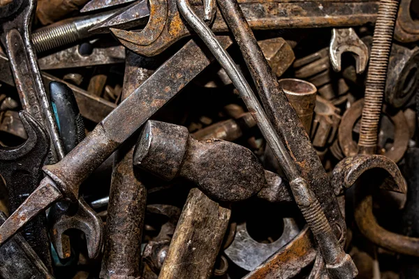 Eski paslı aletler düzensiz. Ön planda bir çekiç, bir ingiliz anahtarı ve bir keski. Arkaplan dokusu kapat.