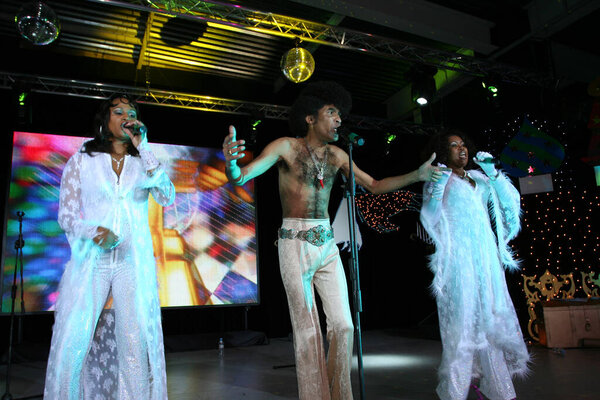 Brovary, Ukraine, 30.12.2006 Concert of the Boney M vocal group. Soloists Liz Mitchell, Maizie Williams and Bobby Farrell are singing on the stage. They are dressed in a white concert costumes