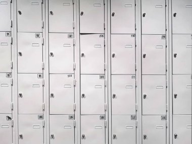 Birkaç sıra içinde numaralar ve kilitler olan gri dolaplar. ön görünüm
