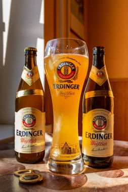 Erdinger birası markalı bir bira bardağına ve iki şişe biraya doldurulur. Erdinger birası masada. 04.07.2015 Kiev Ukrayna