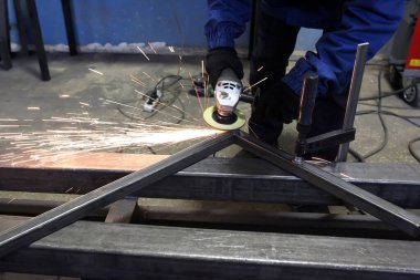 Öğütücü metal. Öğütücü tekerlek. Çilingir, atölyede kaynak yaptıktan sonra demir köşeyi temizler. Kıvılcımlar uçuşuyor.