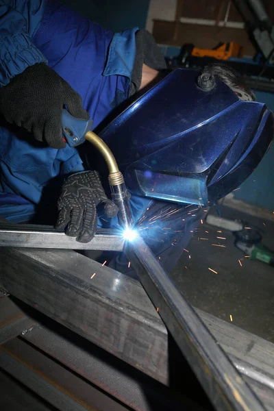 Kaynak. Elektrik yayı kaynaklama. İşçi iki demir köşesini kaynaklıyor..
