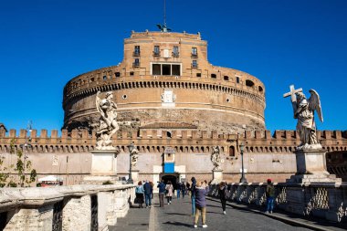 İtalya, Roma 'daki mavi gökyüzüne karşı Sant' Angelo Kalesi 'nin ön manzarası. turistler köprüde yürür