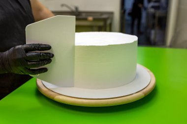 Pasta pişirme. Aşçı beyaz yuvarlak pasta hazırlamak için kalıbı yapar. Beyaz kremalı Daub ve spatulalı pürüzsüz..