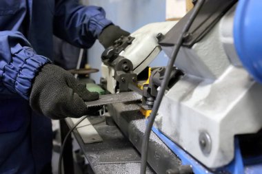 Testere. Bir işçi demir bir parça keser..