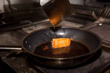 Siyah tavada bir parça kırmızı balık. Mutfakta kızarmış balık..