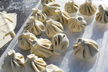 Khinkali pişiriyorum. Çiğ hamurdan yapılmış Khinkali un serpiştirilmiş bir tezgahta yatıyor, yemek pişirmek için kırmızı bir hamur. Yakın plan. Gürcistan ulusal yemeği.