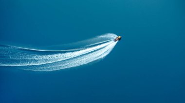 The jet ski travels at great speed through blue water, leaving a foamy trail. View from above clipart