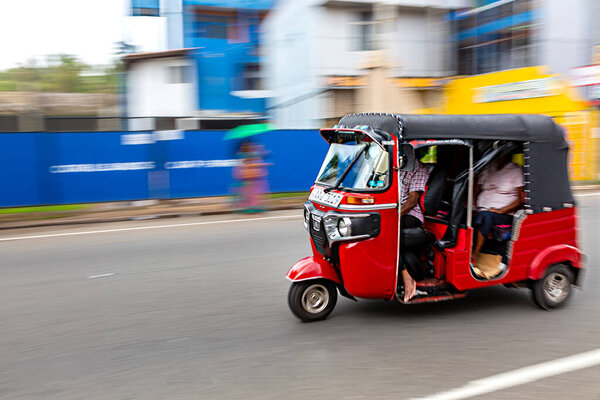 Tuk-tuk red from Sri Lanka, in motion blur. Auto rickshaw rides at high speed