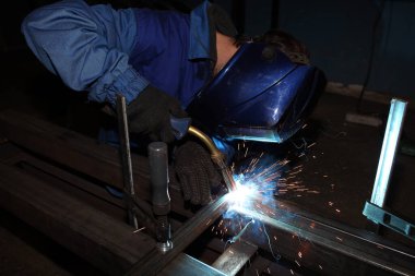 Kaynak. Elektrik yayı kaynaklama. İşçi iki demir köşesini kaynaklıyor..