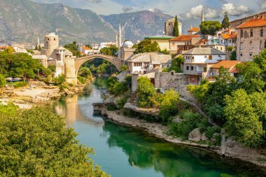 Bosna-Hersek 'teki Mostar köprüsü. Mostar şehrinde bir köprüsü ve zümrüt bir nehri olan renkli bir manzara..